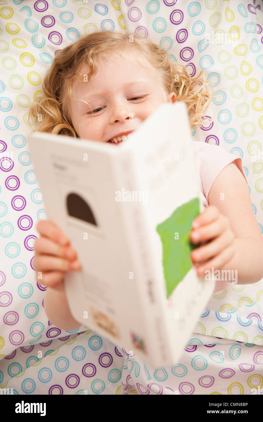 Caucasian Girl Reading Book In Bed Stock Photo Alamy