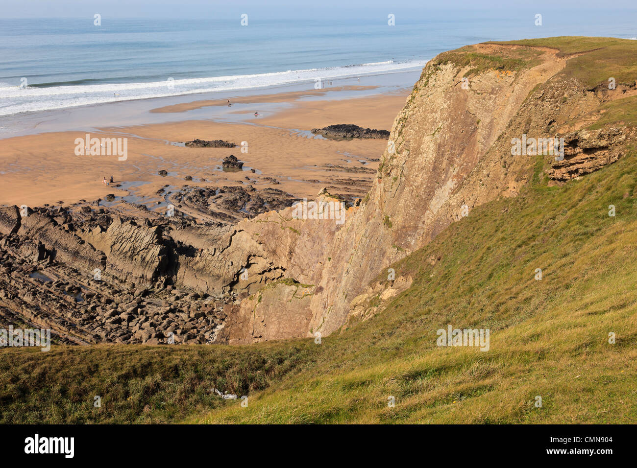 Vertical beds of Carboniferous sandstone cliffs above the beach on Cornish coast in Bude Bay, North Cornwall, England, UK Stock Photo
