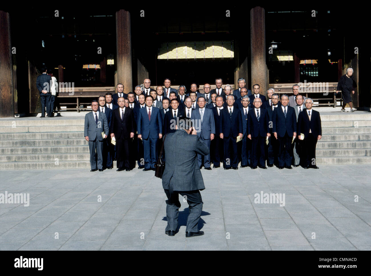A group of serious Japanese businessmen in suits and ties pose for a formal photographic portrait on the steps of the Meiji Shrine in Tokyo, Japan. Stock Photo