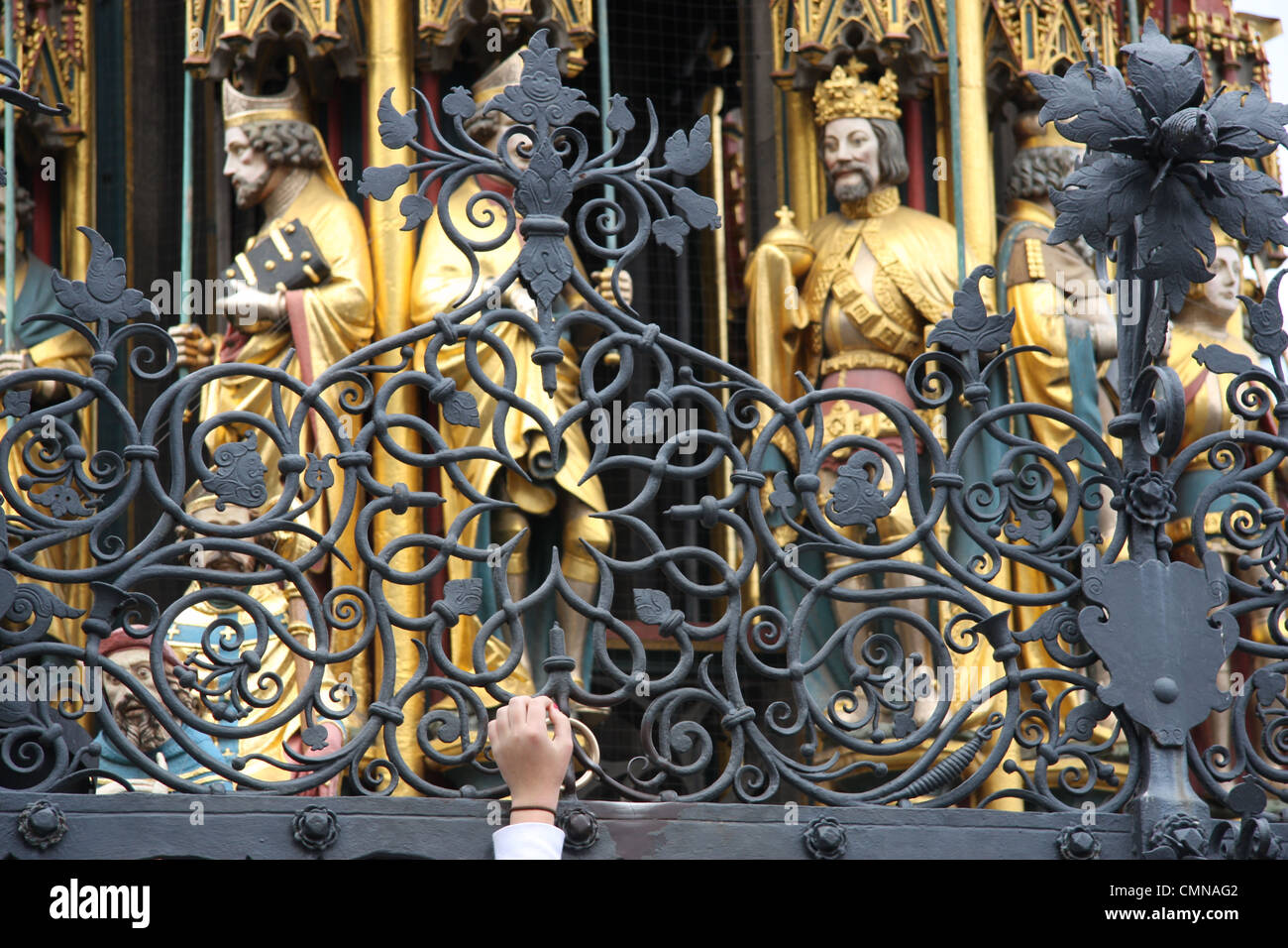 Tourist rubs the brass ring set in the wrought iron fence of the beautiful fountain in the market square at Nuremberg, Germany Stock Photo