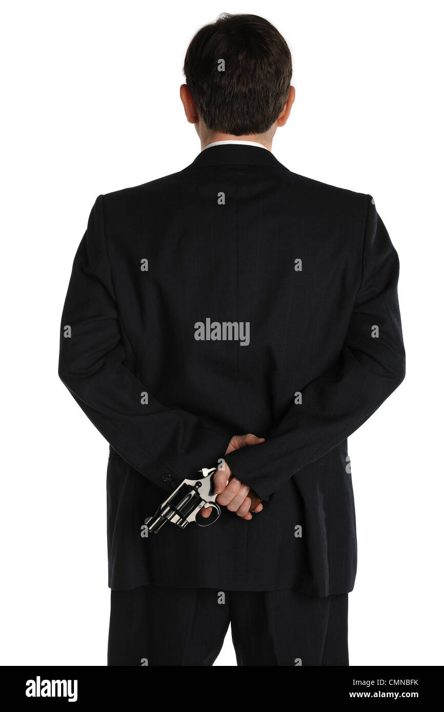 A man in a business suit hides a pistol behind his back Stock Photo