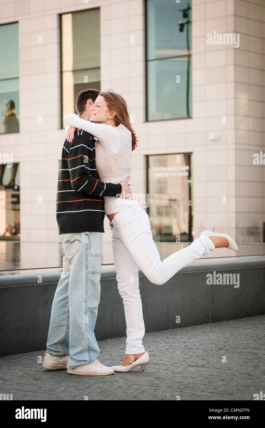 Happy couple - young man welcomes her girlfriend on street - full lenght composition Stock Photo
