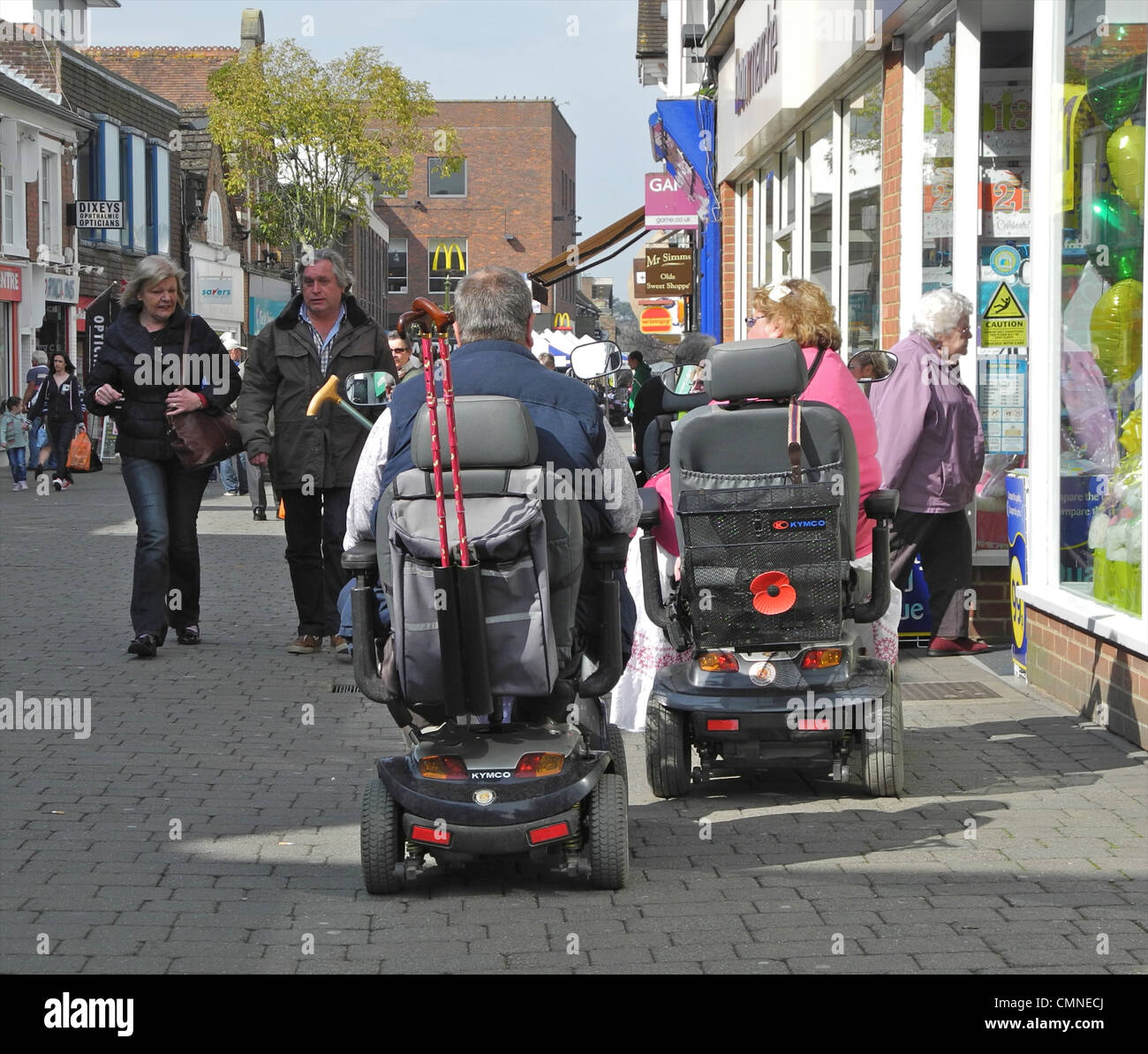 People using mobility scooters in a shopping centre, town centre. THIS IMAGE IS EDITORIAL ONLY AND MUST NOT BE USED IN ANY WAY THAT DEMEANS THE USERS OF THE SCOOTERS this is in West Street, Horsham, West Sussex. Stock Photo