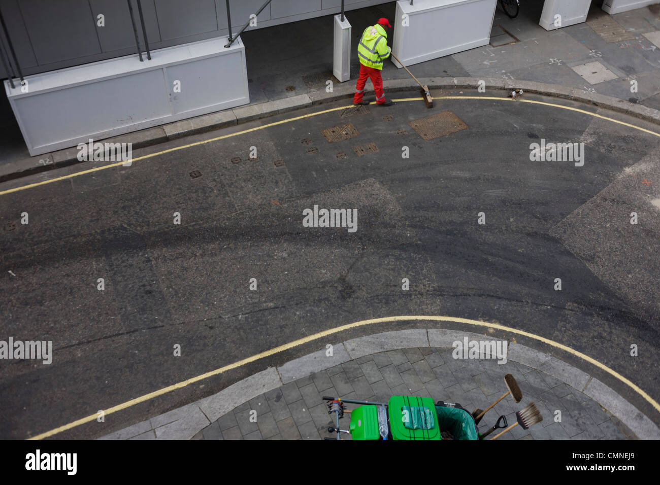 Aerial view of a corporation of London contract street sweeper brushes litter in the gutter of a City street. Stock Photo