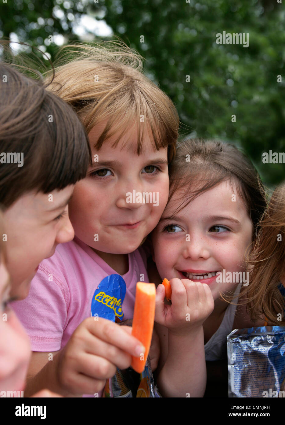 Girls eating raw carrots in Hyde Park London Stock Photo