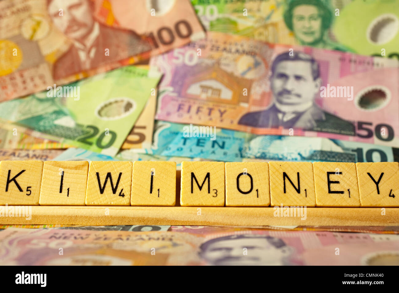 New Zealand Currency and Scrabble tiles spelling out the words Kiwi Money. Stock Photo