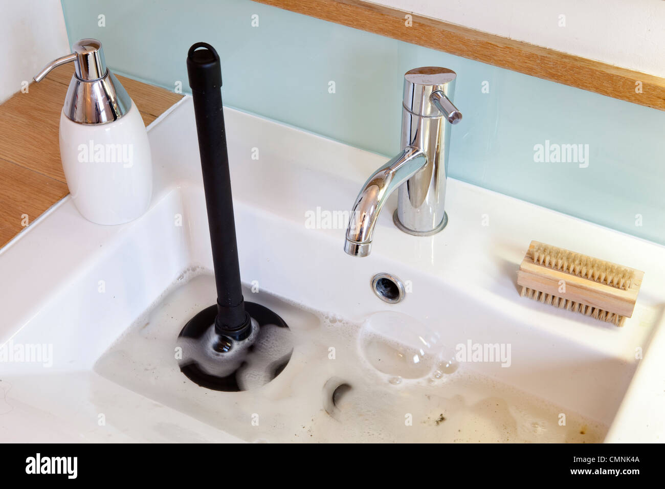 Blocked bathroom sink with plunger Stock Photo