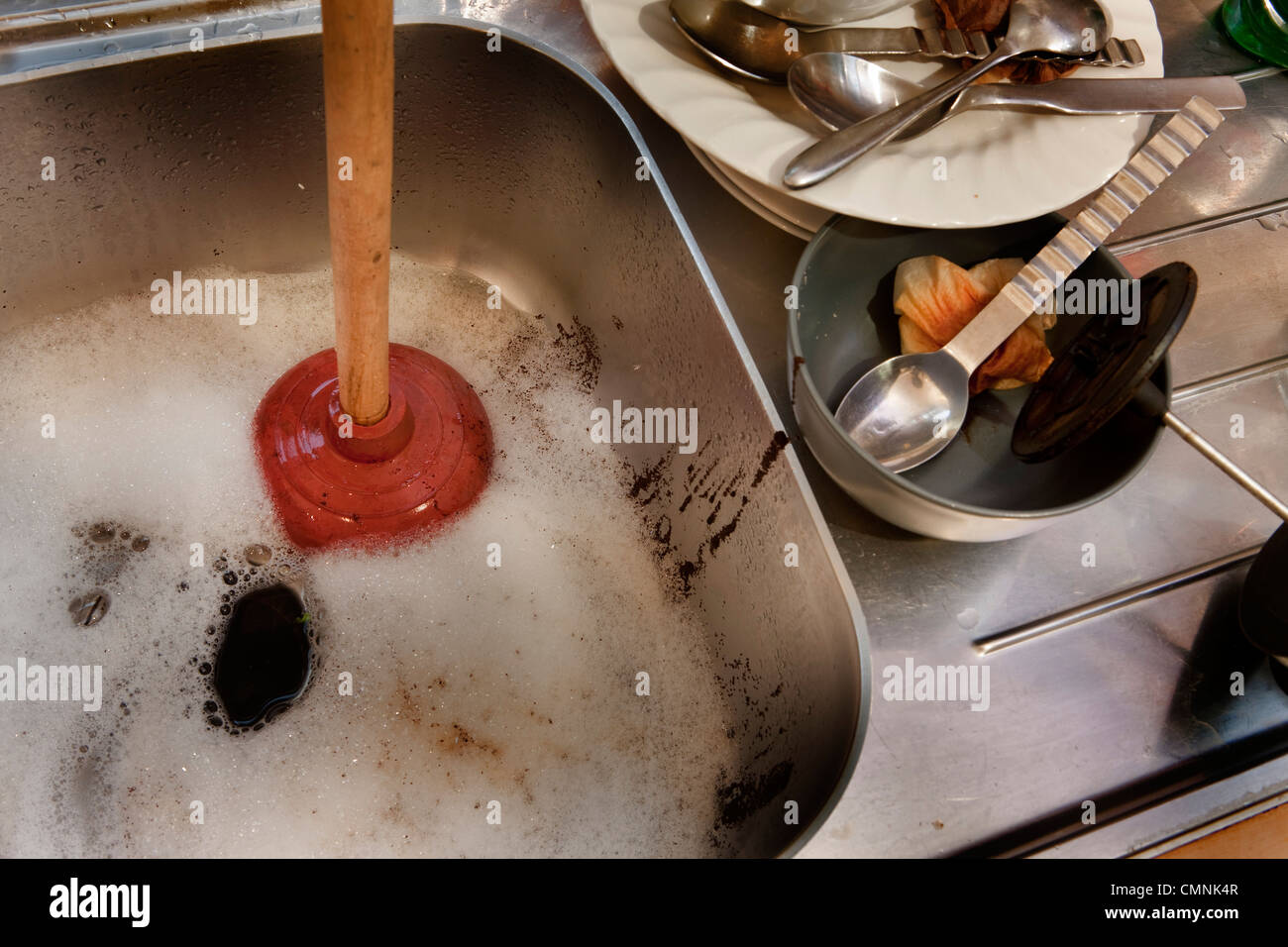 Blocked kitchen sink with plunger Stock Photo
