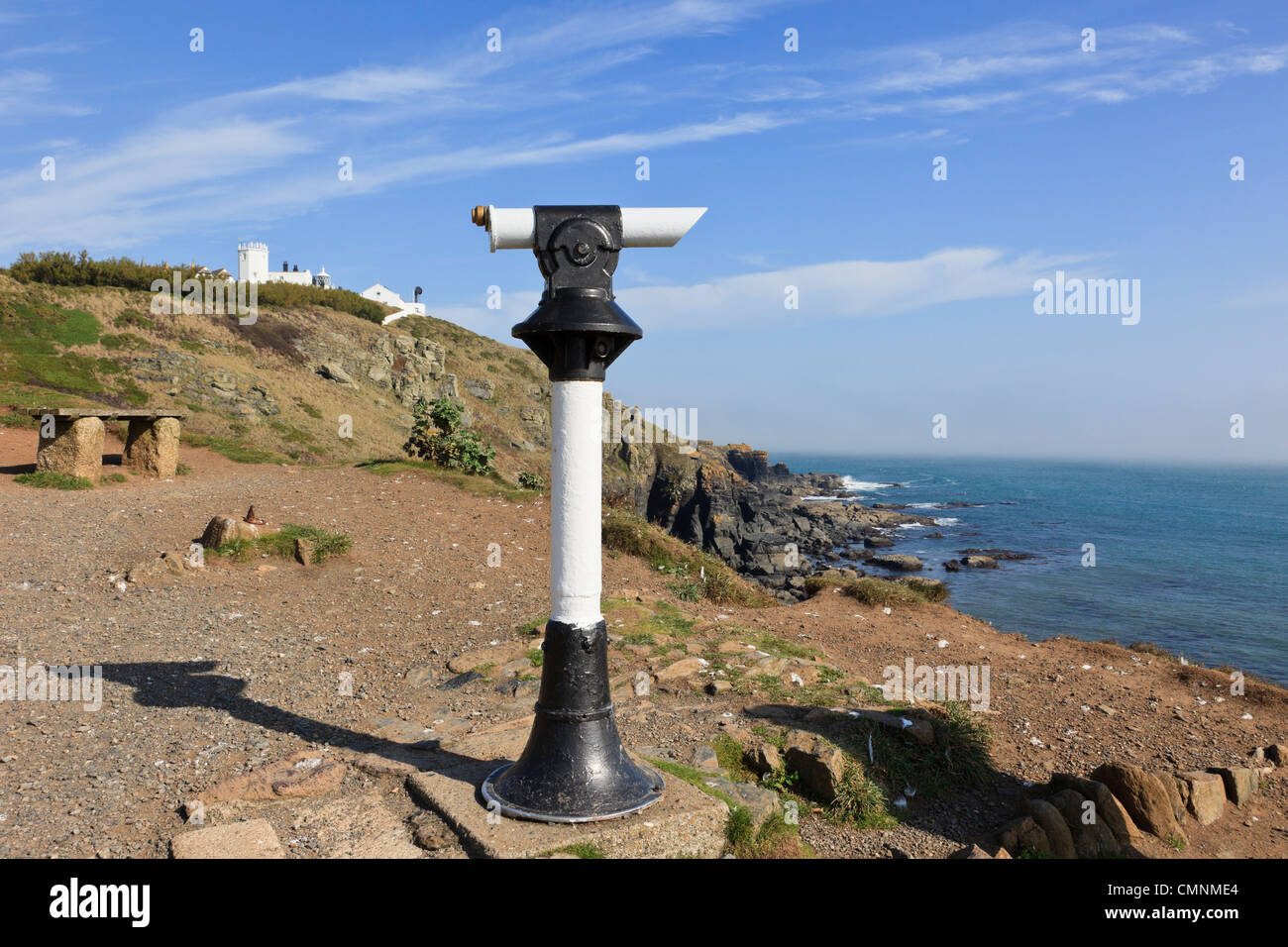 Public telescope on peninsula clifftop looking out over Cornish coast with lighthouse beyond on Lizard Point Cornwall England UK Stock Photo