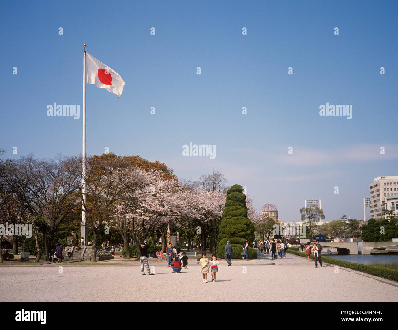 Japan Hiroshima Peace Park Japanese flag flying with Industrial Promotion Hall (A-Bomb Dome) in distance  Stock Photo