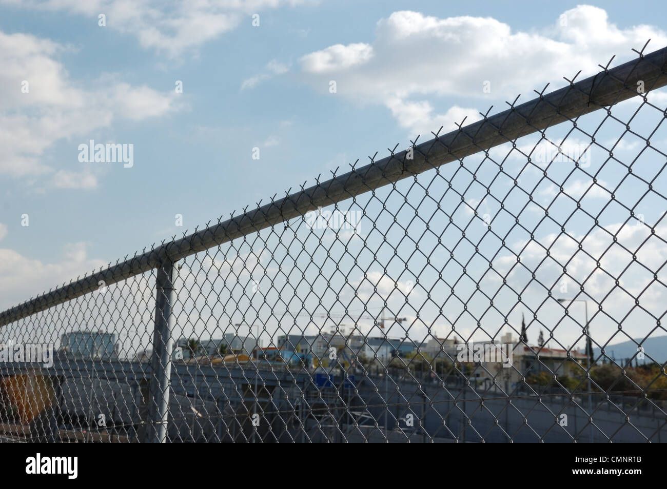 Cityscape through chain link fence. Highway barrier above the motorway