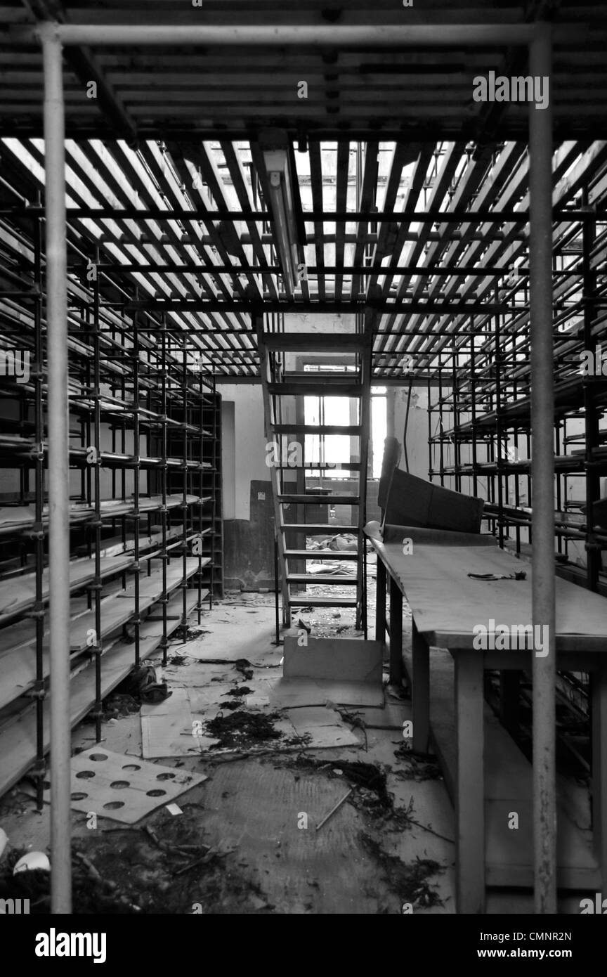 Rows of empty shelves in abandoned factory storage room. Black and white. Stock Photo