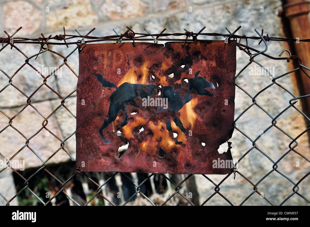 Rusty beware of the dog sign and chain link fence background. Stock Photo