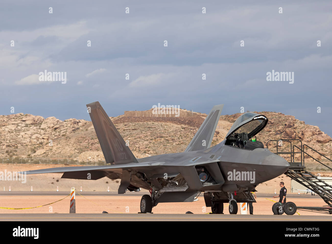 Aircraft F-22 Raptor USAF air supremacy superiority fighter aircraft and crew by runway. Desert location. Stock Photo
