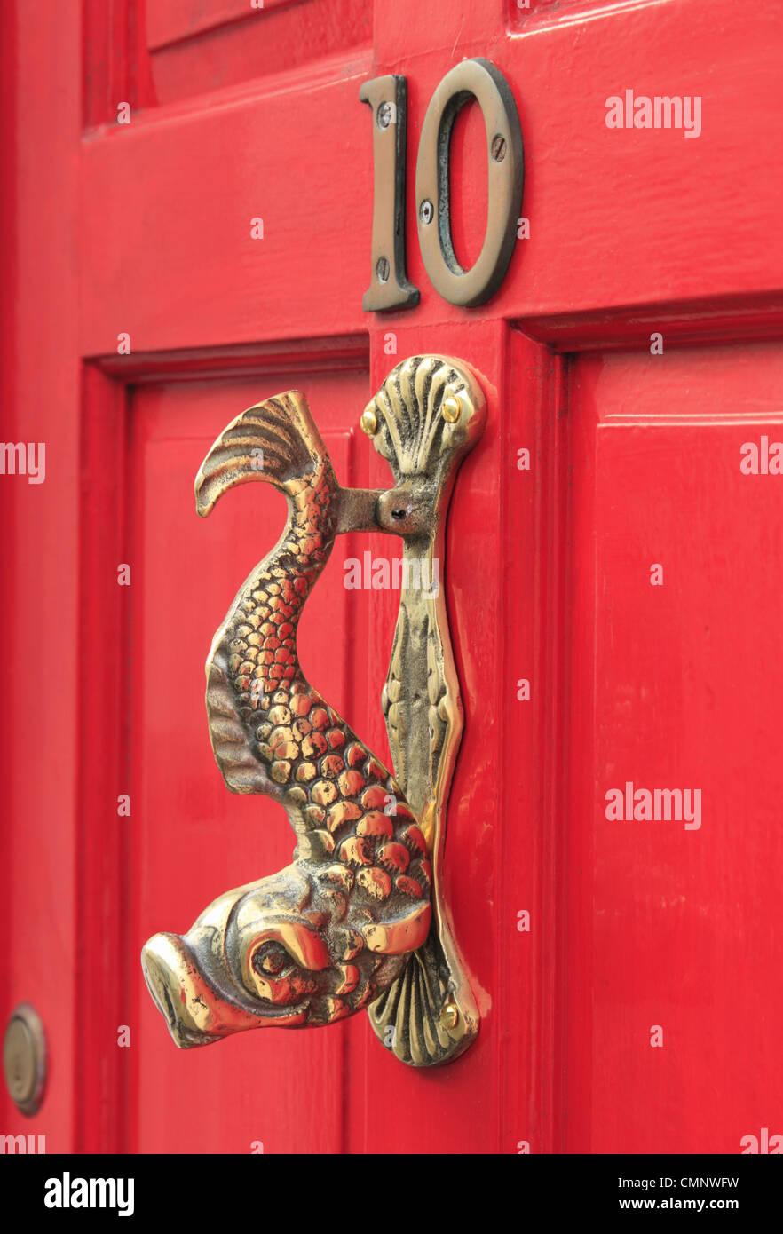 A brass door knocker in the shape of a fish on a red front door number ten 10 in the town of Lewes, East Sussex, England Stock Photo
