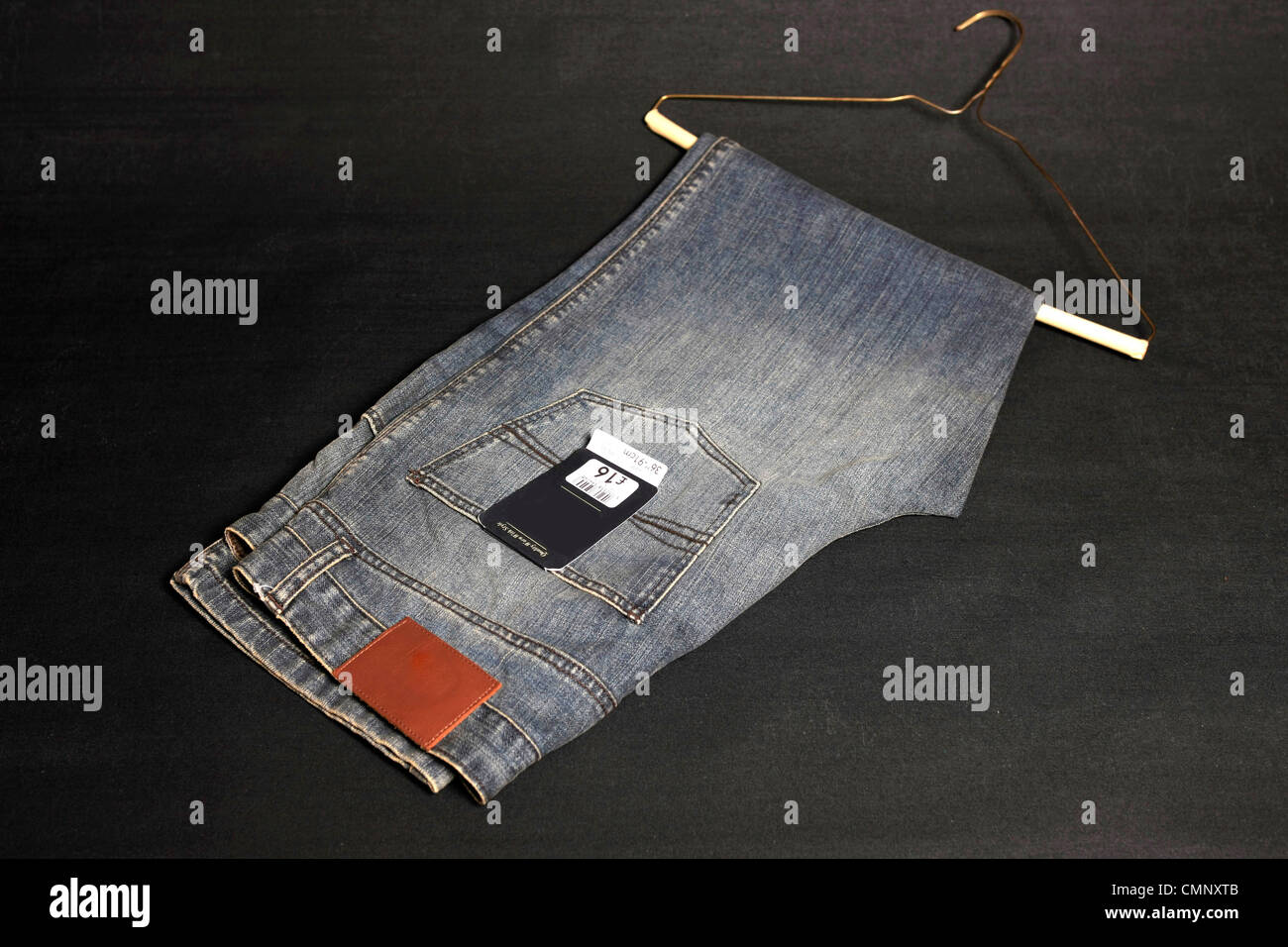 A pair of black stone washed jeans on a black background Stock Photo