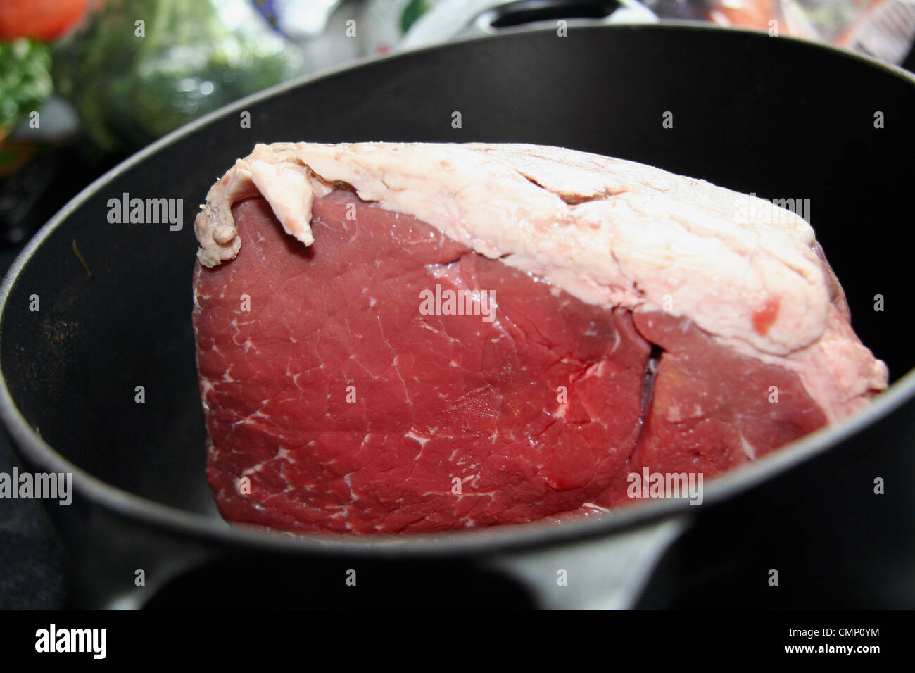 A huge joint of beef ready to roast in a black Le Creuset pan Stock