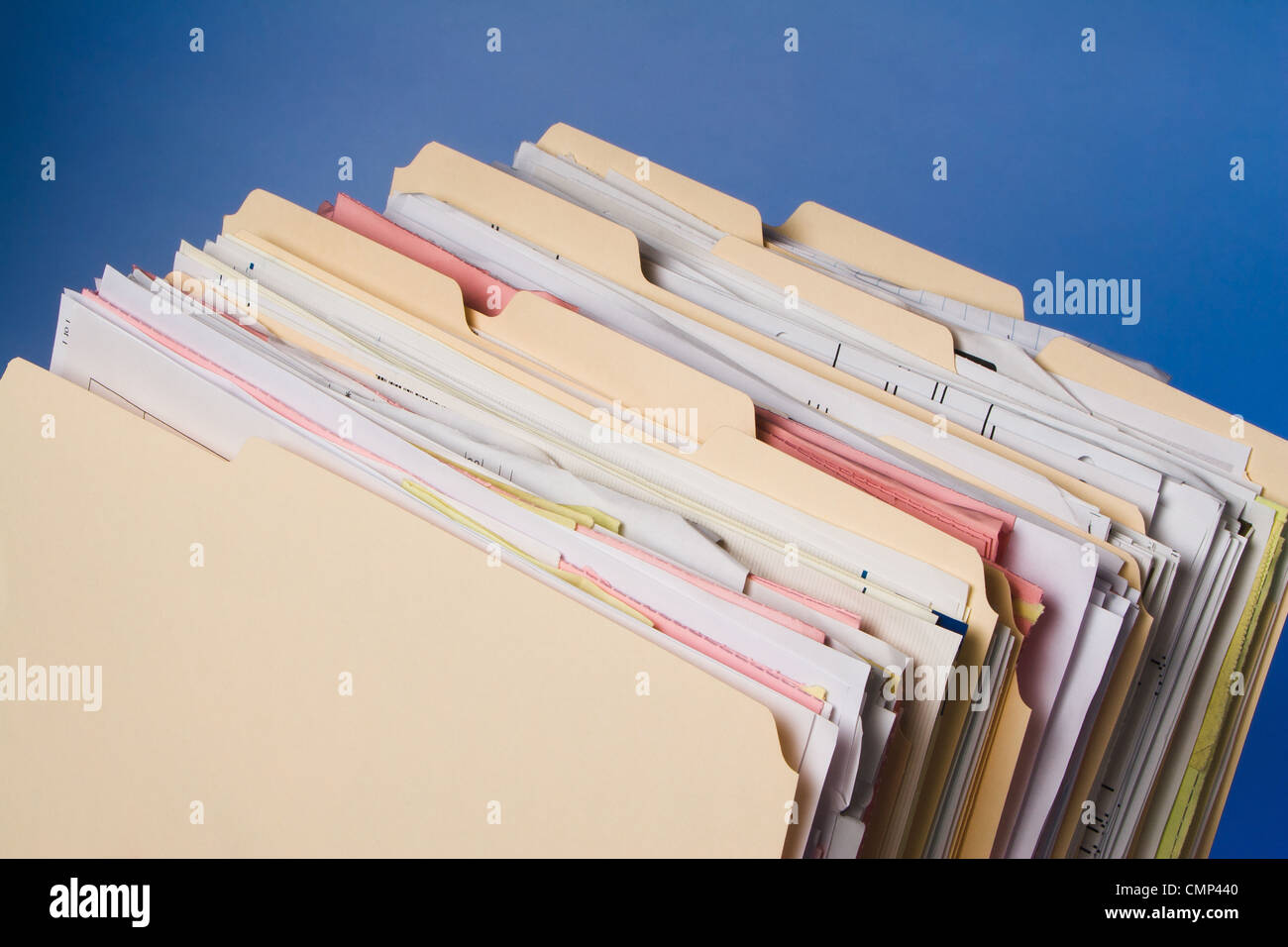 Many filled manila folders stacked upright against blue background