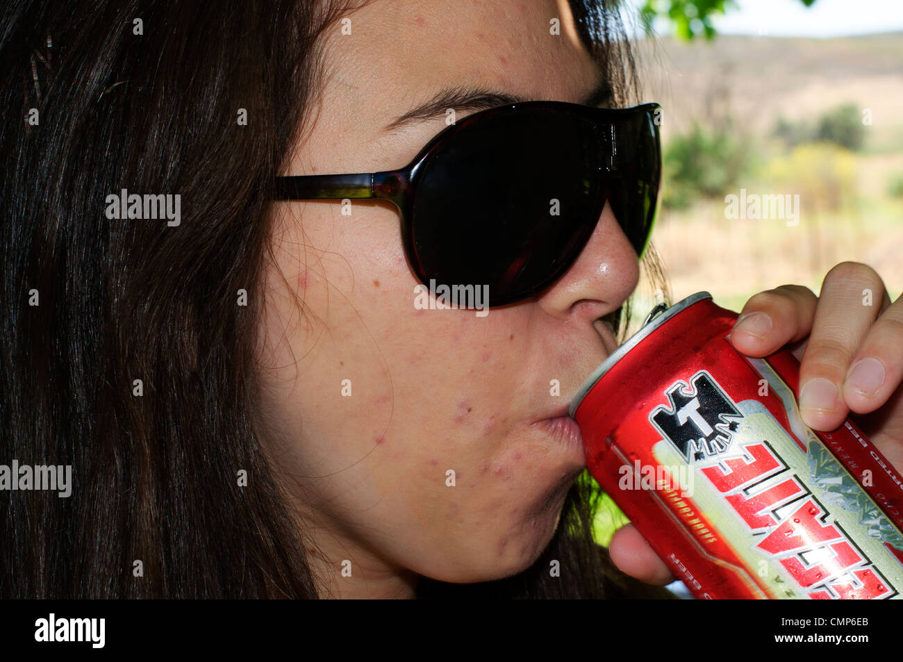 Young hispanic woman drinking a can of Tecate beer in a ranch environment Stock Photo