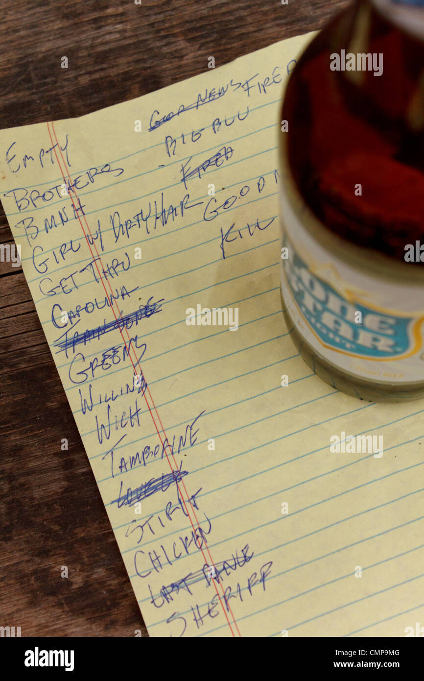 Rock band's set list handwritten in a torn yellow paper with an empty bottle beer sitting on top of it. Stock Photo