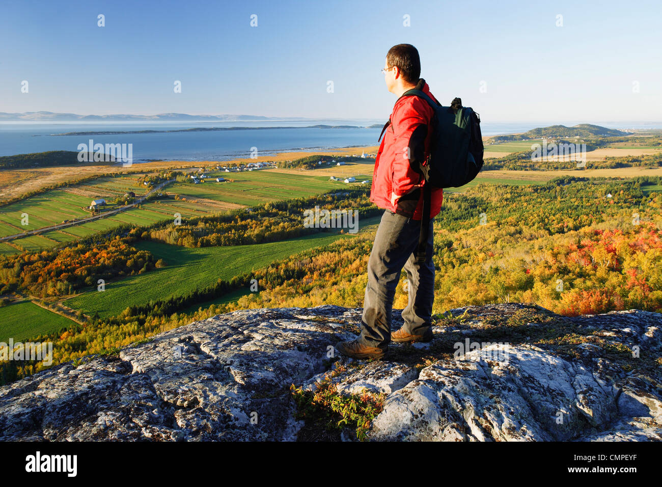 Hiker over looking Kamouraska Village and St. Lawrence River at Sunset, Bas-Saint-Laurent Region, Quebec Stock Photo