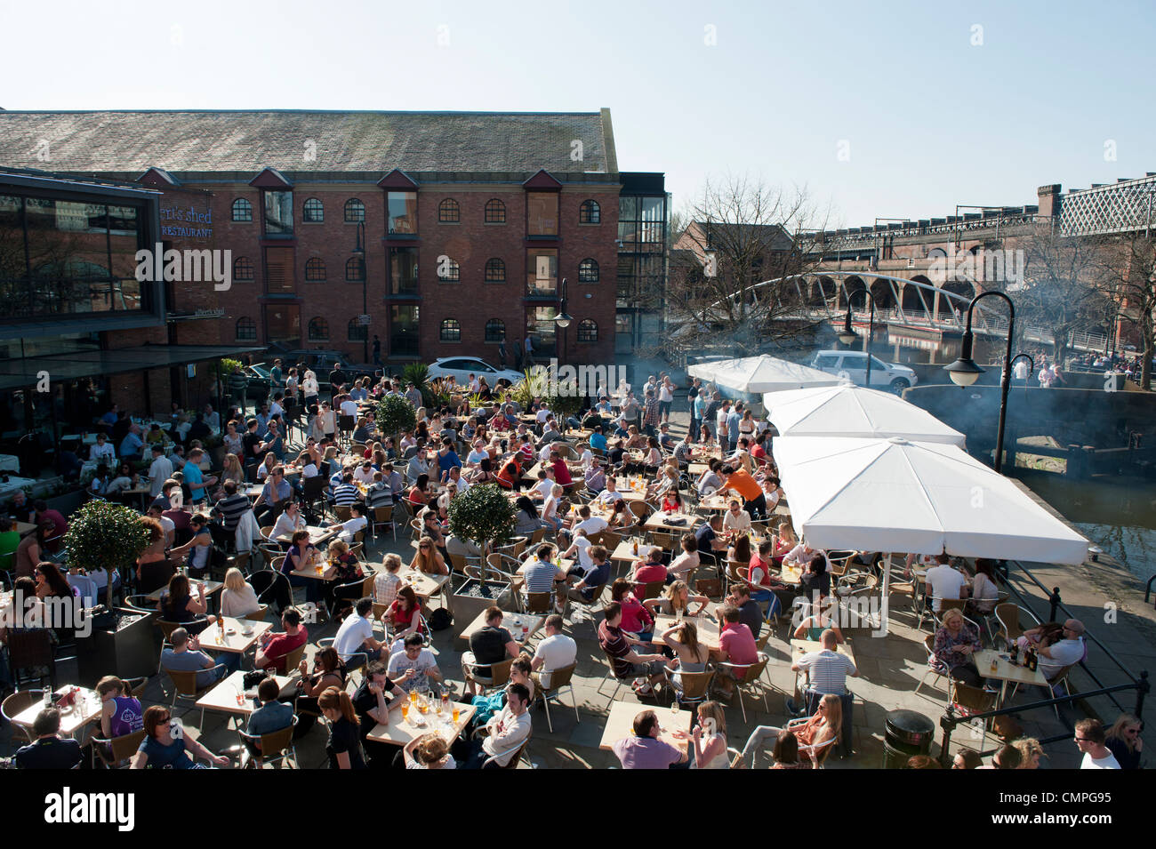 Revellers enjoy the evening sunshine in a beer garden in Castlefield in Manchester (Editorial use only). Stock Photo