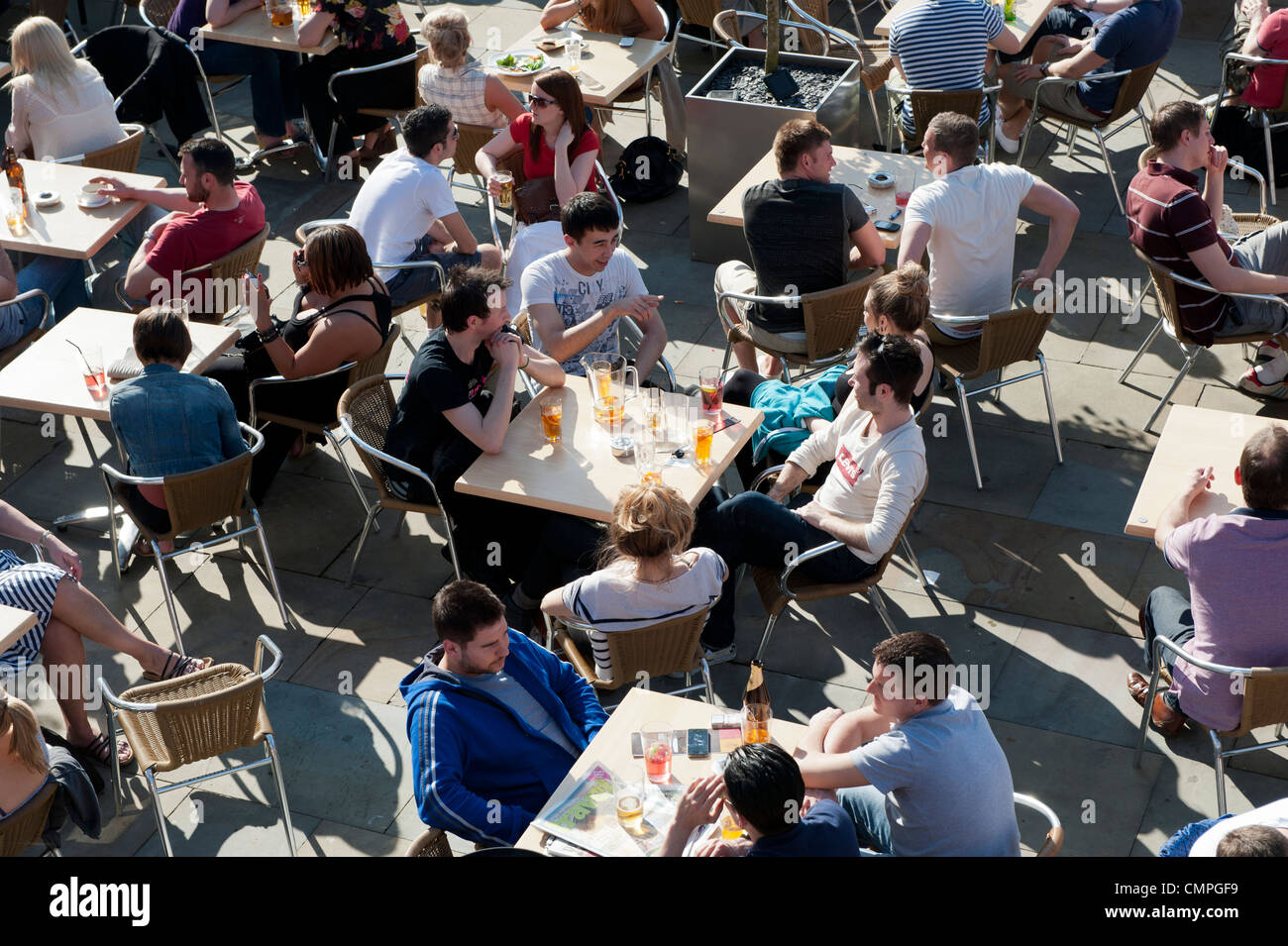 Revellers enjoy the evening sunshine in a beer garden in Castlefield in Manchester. Stock Photo