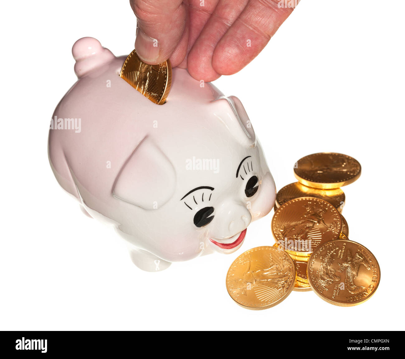 Fingers placing a single gold coin into the slot on a piggy bank and ...