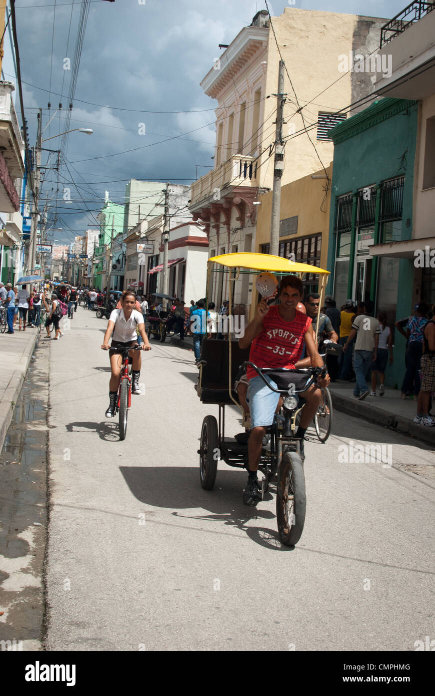 street scene, rickshaw, person on a bicycle, Calle Republica/ Republic street in Camaguey Stock Photo