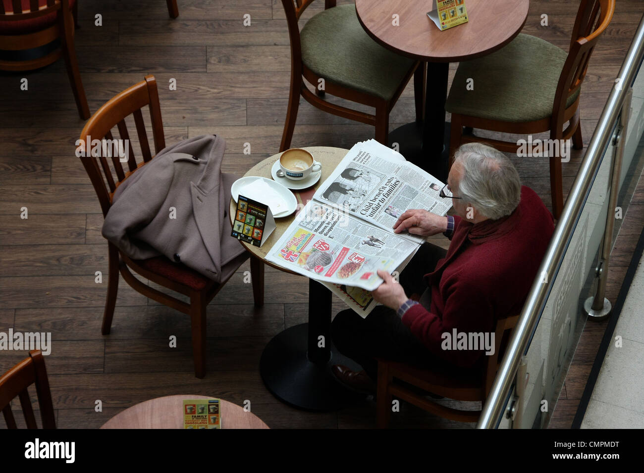 Reading paper at table at coffee stall. Stock Photo