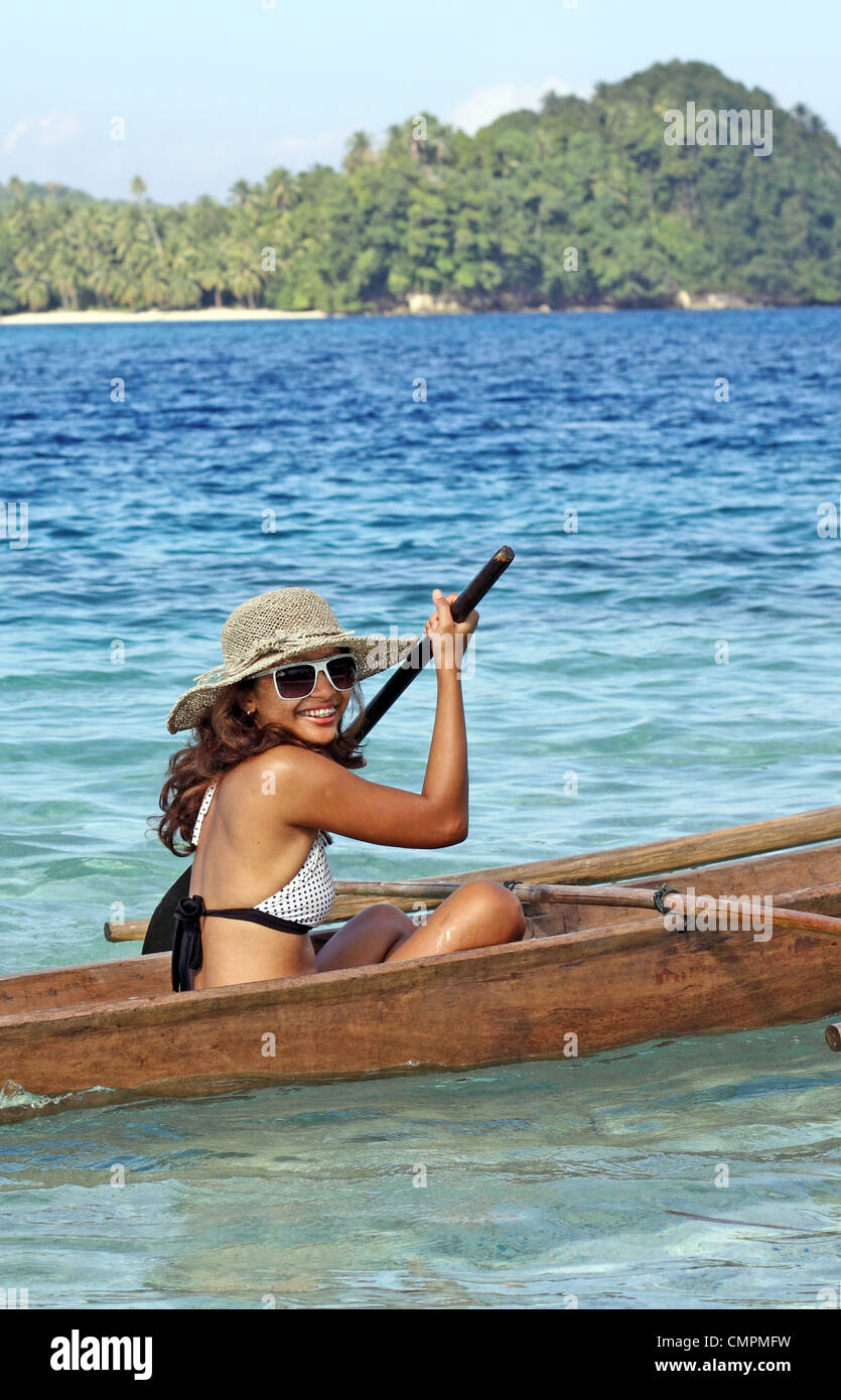 Young woman paddling outrigger canoe. Simakakang, Mentawai Islands, West Sumatra, Sumatra, Indonesia, South-East Asia, Asia Stock Photo