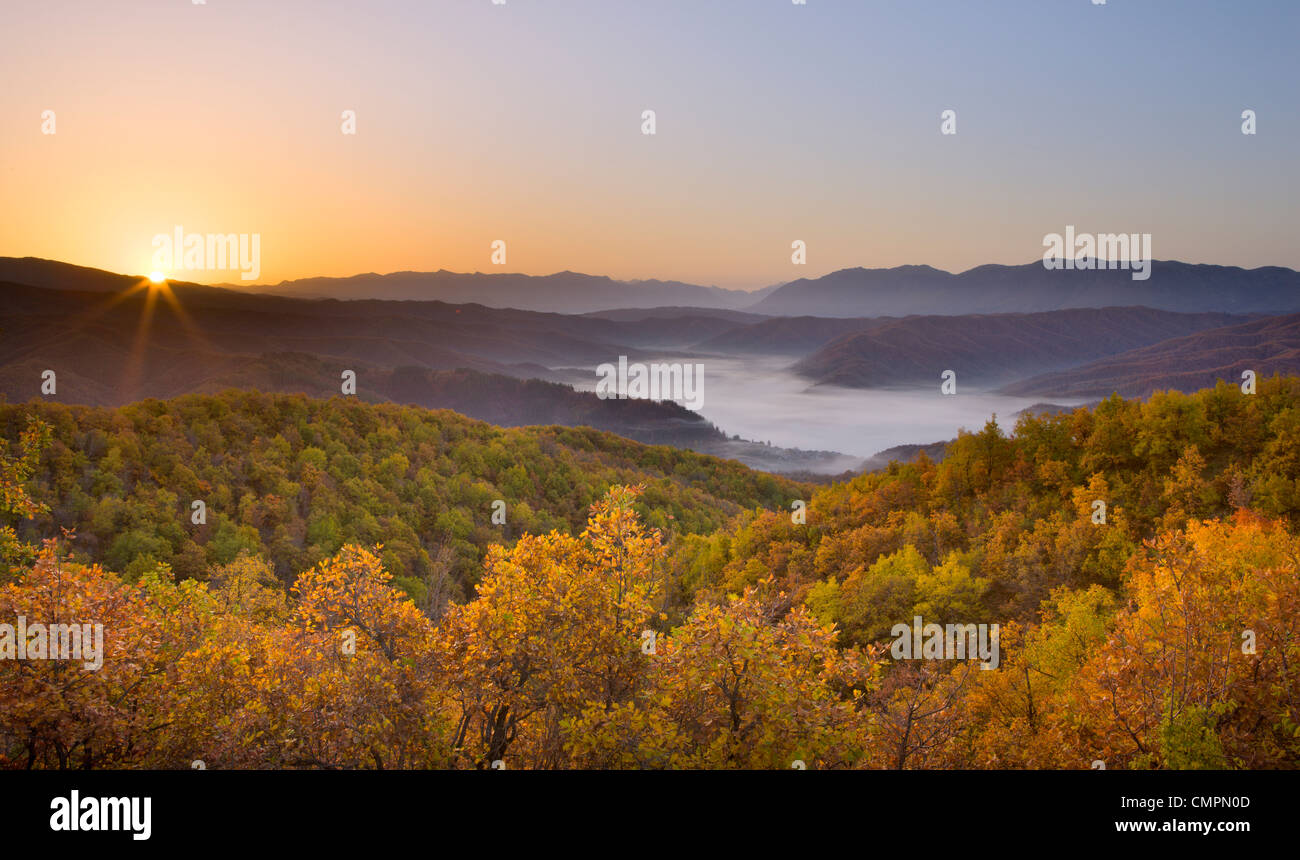 Autumn sunrise in Zagoria with the village of Kipi and a mist filled valley below, Epirus, Greece, Europe Stock Photo