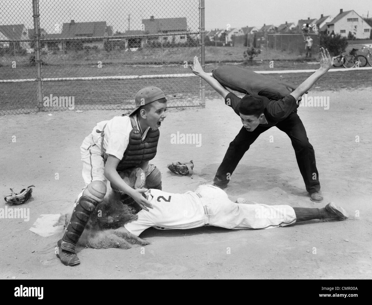 1950s LITTLE LEAGUE UMPIRE CALLING SAFE PLAYER SLIDING INTO HOME PLATE Stock Photo