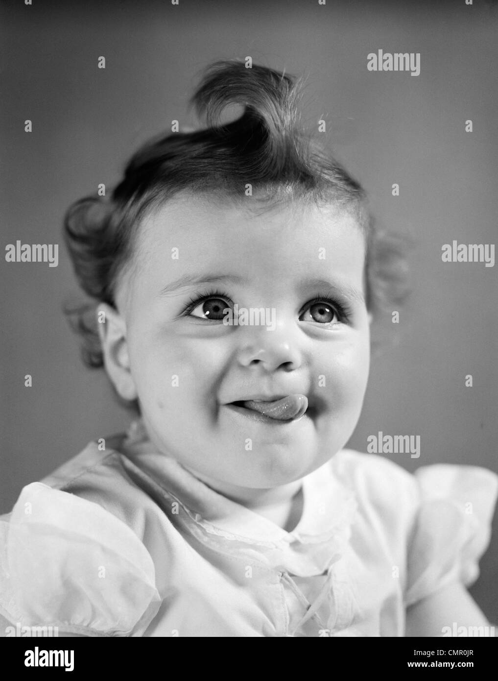 1940s BABY GIRL SMILING STICKING OUT HER TONGUE Stock Photo
