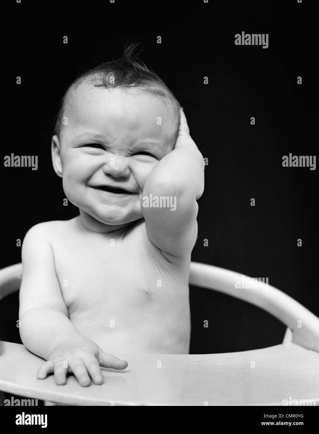 1940s PORTRAIT OF BABY SMILING HOLDING HAND TO SIDE OF HEAD Stock Photo