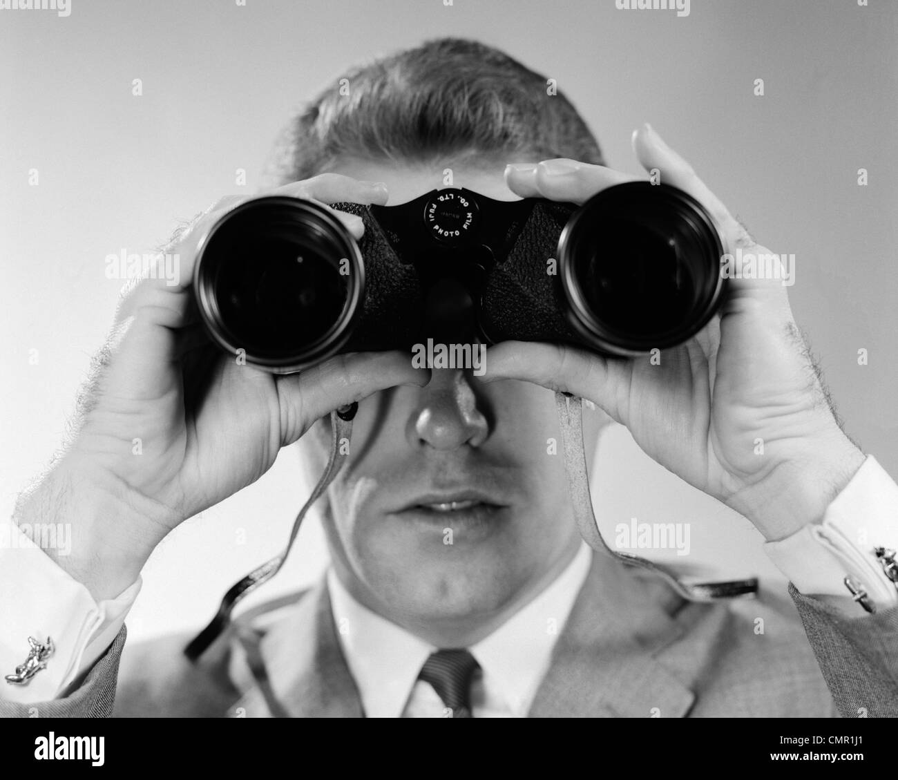 1960s HEAD-ON CLOSE-UP OF MAN LOOKING THROUGH BINOCULARS Stock Photo