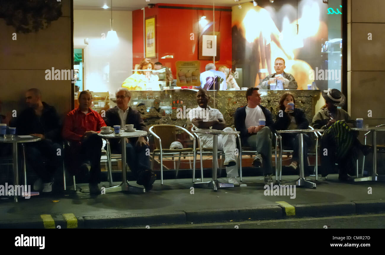 Cosmopolitan group of people sitting outside a Soho Cafe at night Stock Photo