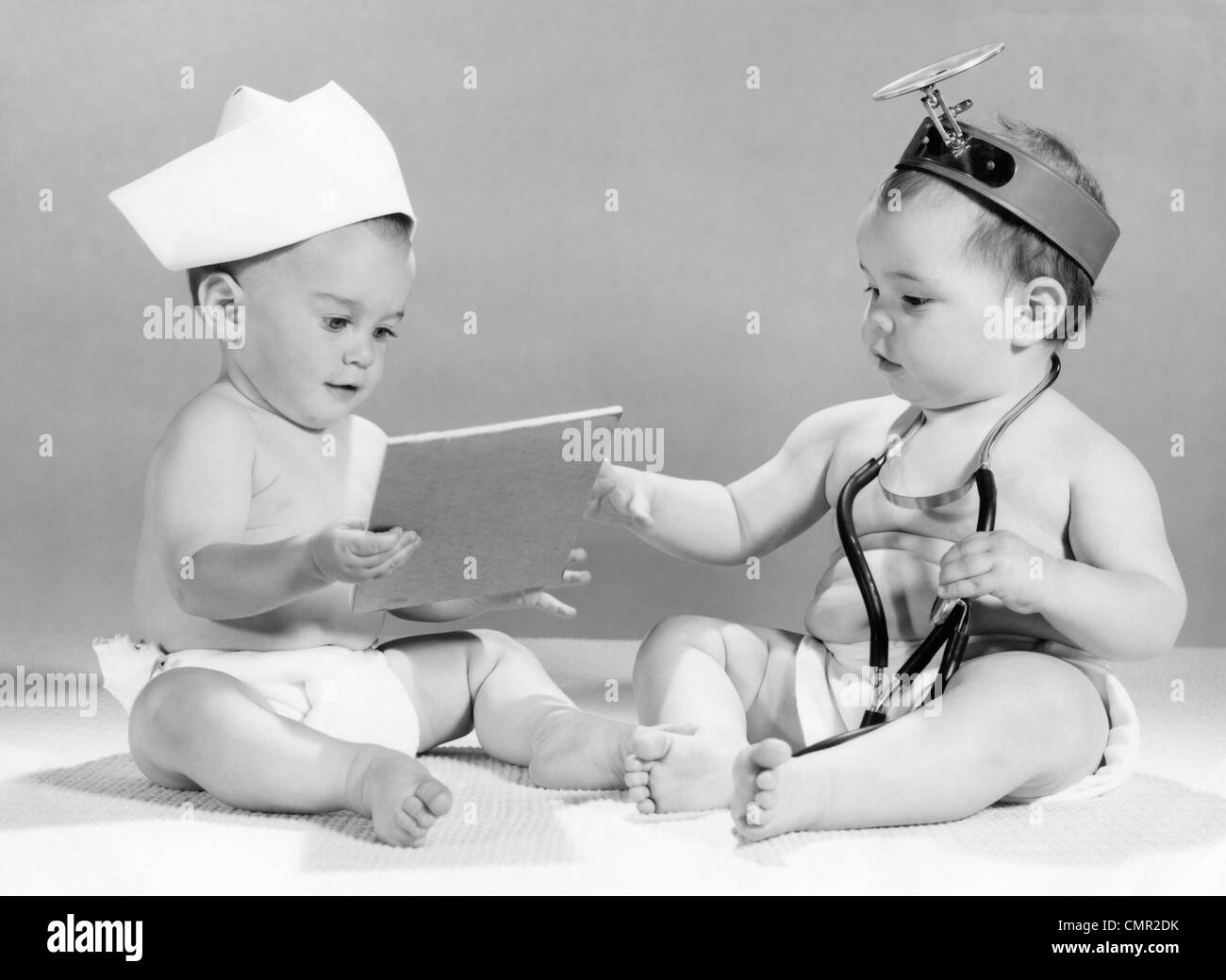 1960s BABY DOCTOR AND NURSE WITH CHART AND STETHOSCOPE Stock Photo