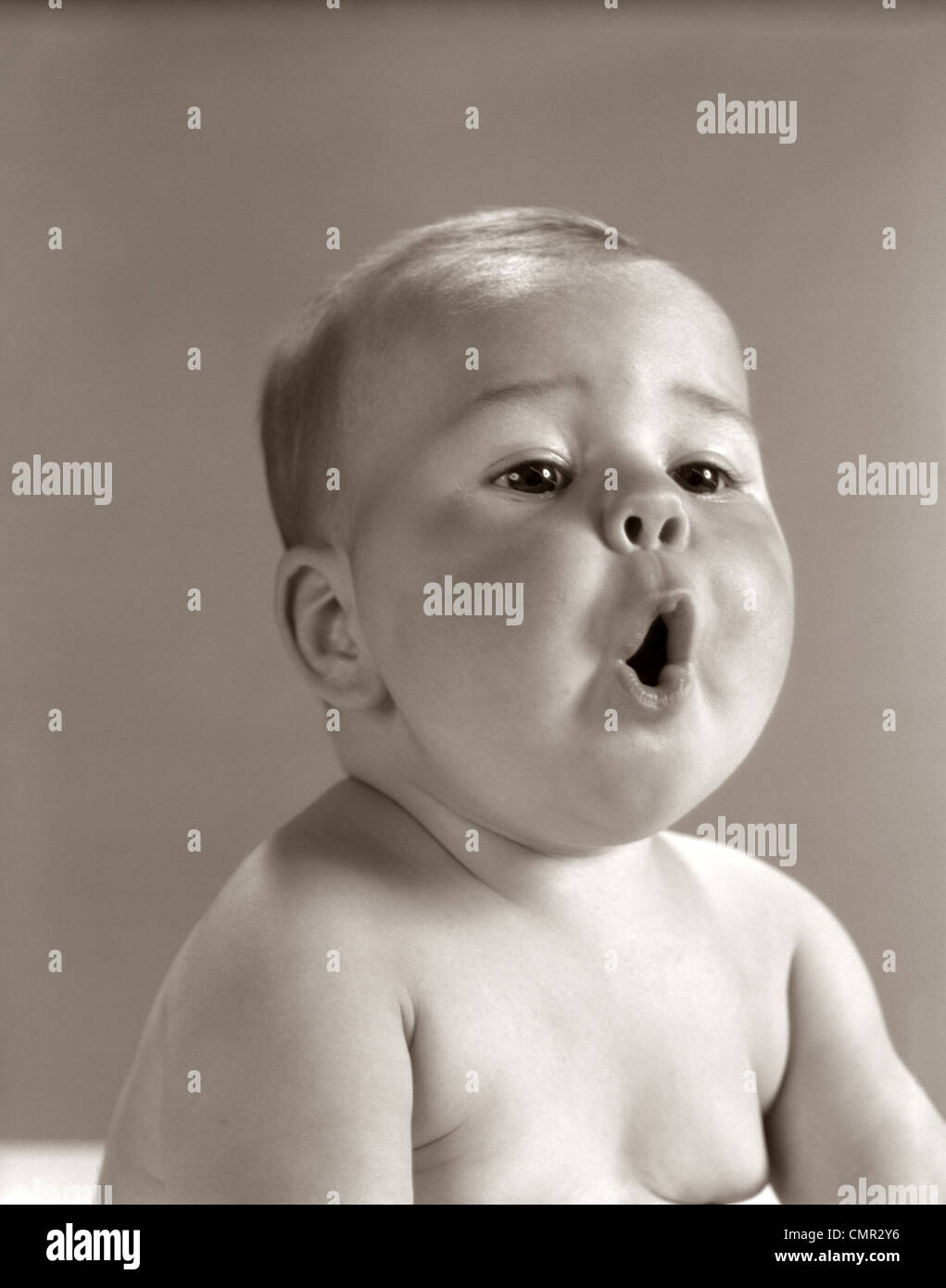 1960s PORTRAIT BABY WITH CHUBBY CHEEKS MAKING O SHAPE WITH MOUTH Stock