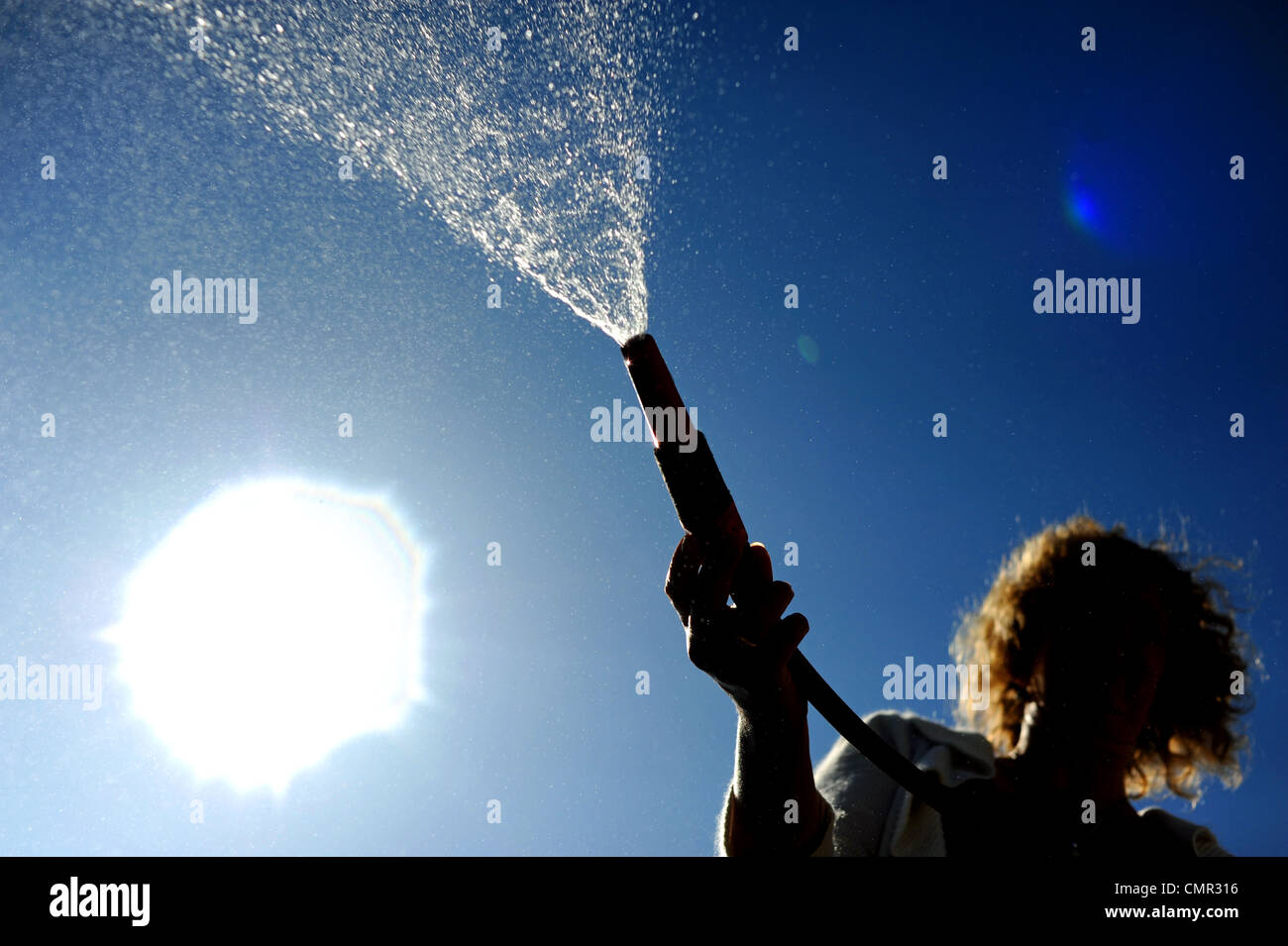 Woman using a garden hose . There are hosepipe bans planned for some parts of the south of England as rainfall is low Stock Photo