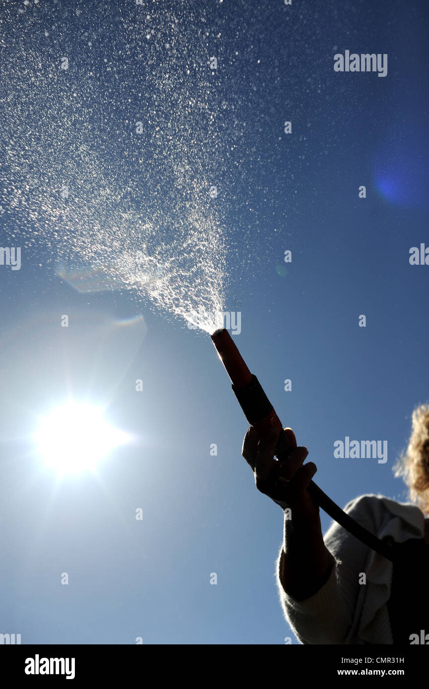 Woman using a garden hose . There are hosepipe bans planned for some parts of the south of England as rainfall is low Stock Photo