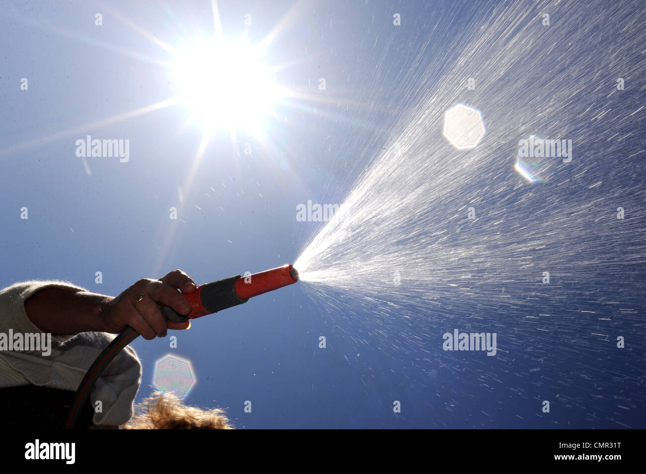 Woman using a garden hose . There are hosepipe bans planned for some parts of the south of England as rainfall is low Stock Photo