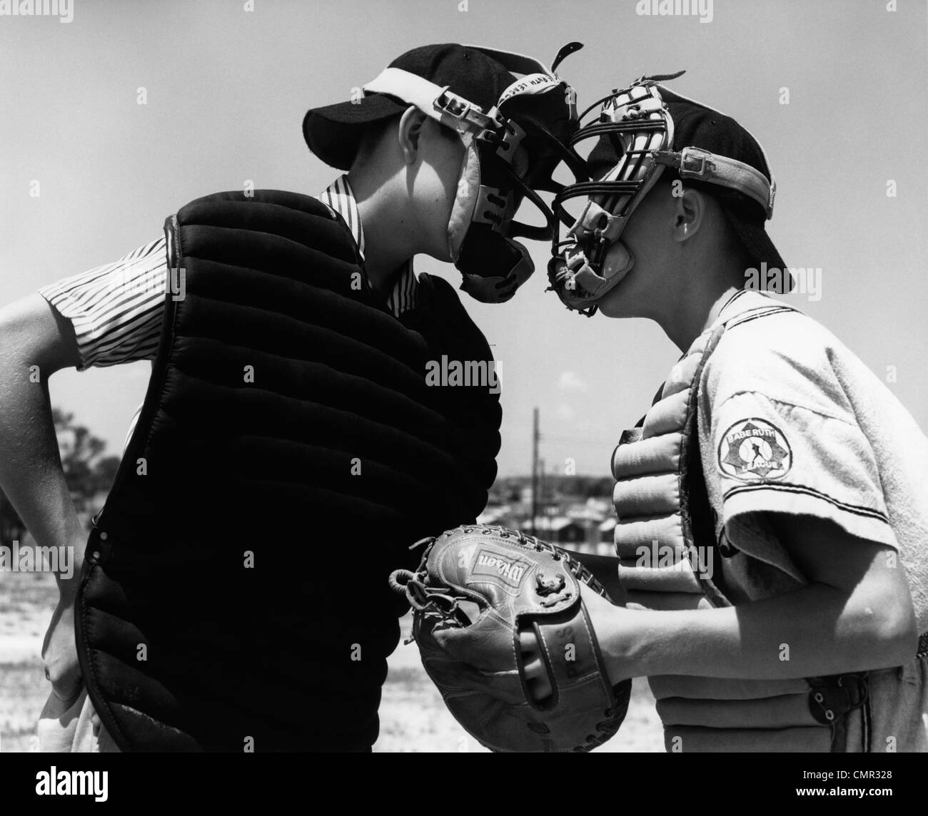 1950s 1960s CLOSE-UP OF LITTLE LEAGUE UMPIRE & CATCHER ARGUING FACE TO FACE Stock Photo