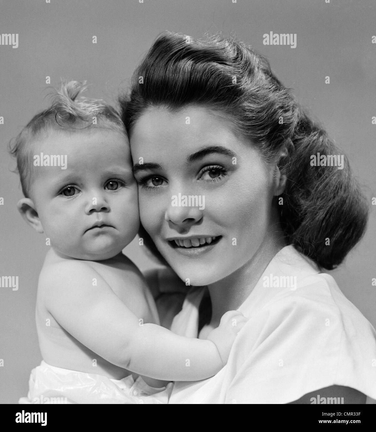 1940s 1950s PORTRAIT OF MOTHER HUGGING BABY LOOKING AT CAMERA Stock Photo