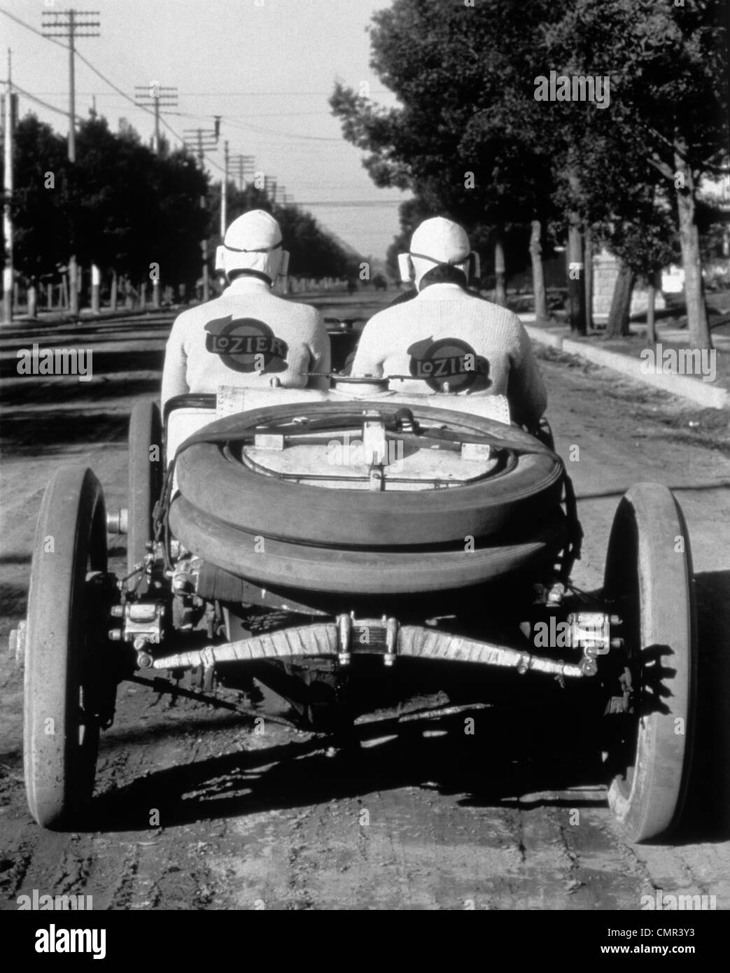 1900s 1910s REAR VIEW OF TWO MEN SITTING IN ANTIQUE LOZIER RACING ROAD RALLY CAR Stock Photo