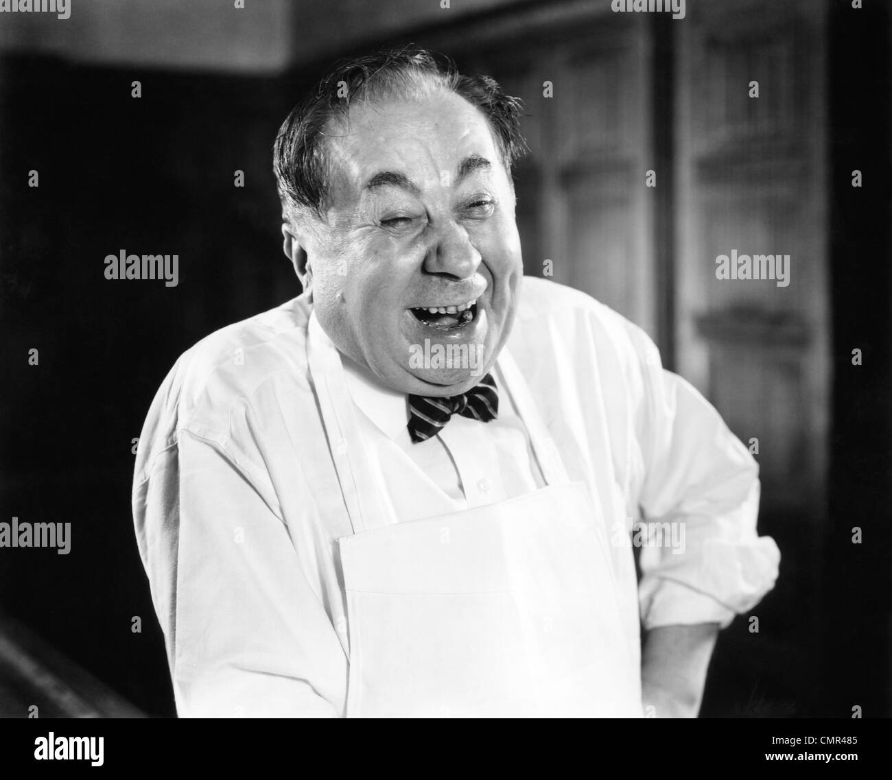 1930s 1940s LAUGHING MAN PORTRAIT WEARING APRON BUTCHER BAKER GROCERY CLERK SERVICE HAPPY MAN Stock Photo