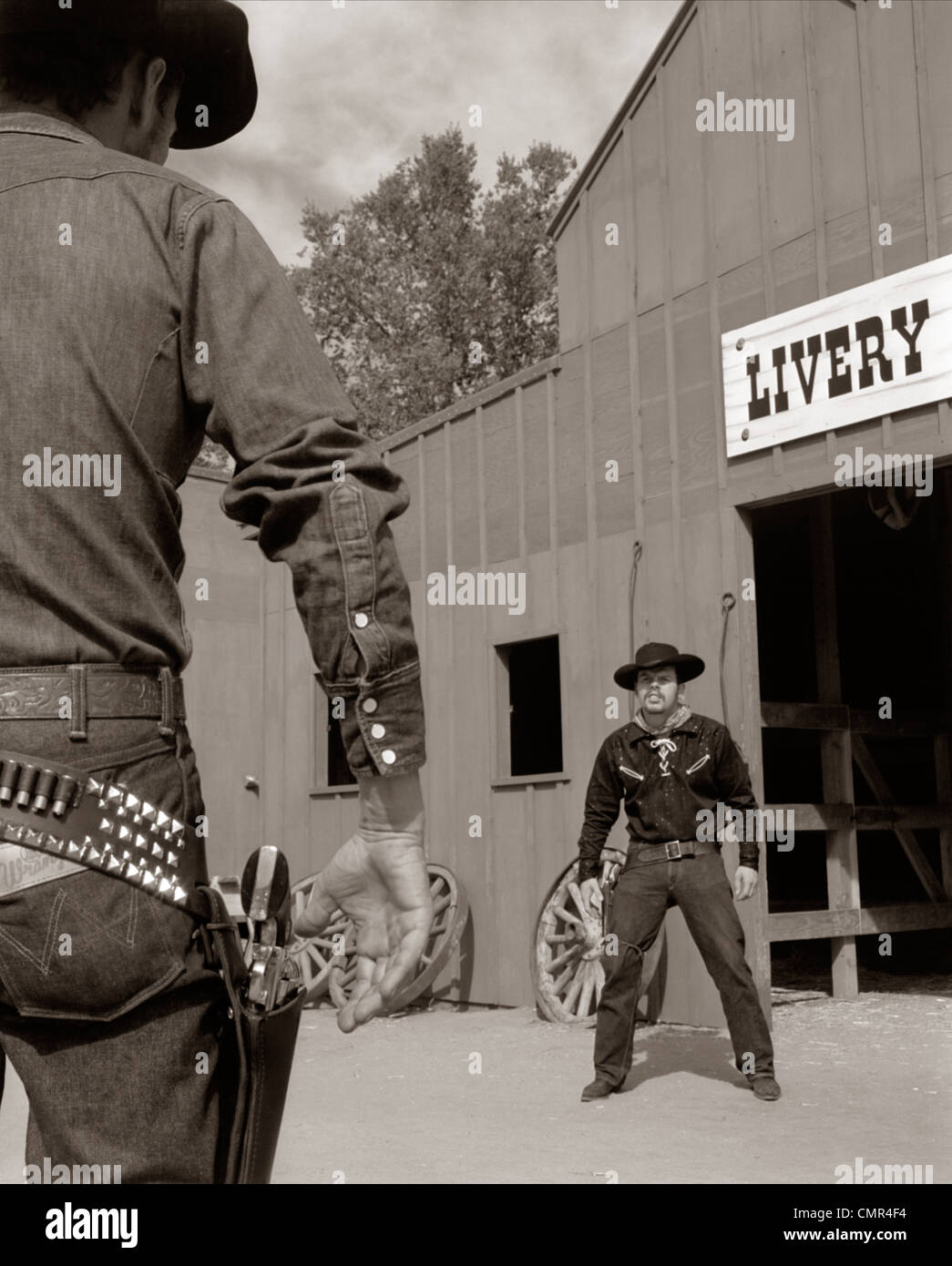 1950s 1960s TV COWBOYS IN FRONT OF LIVERY STABLE READY TO DRAW PISTOLS IN GUNFIGHT Stock Photo