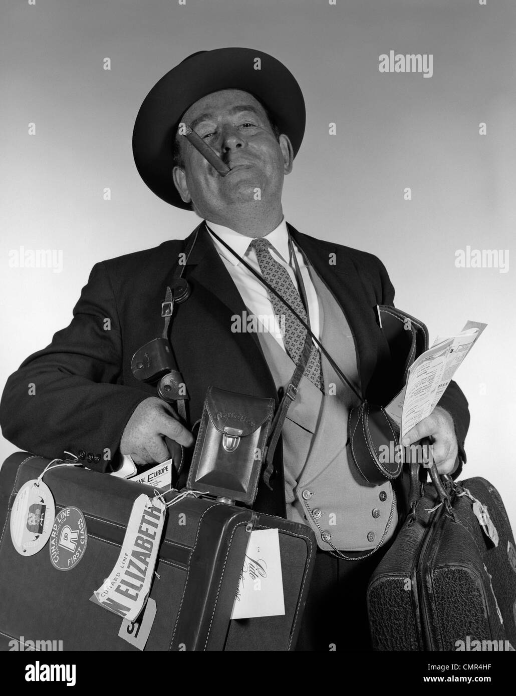 1950s 1960s HEAD-ON PORTRAIT OF CIGAR SMOKING TOURIST CARRYING LOTS OF LUGGAGE LOOKING AT CAMERA Stock Photo