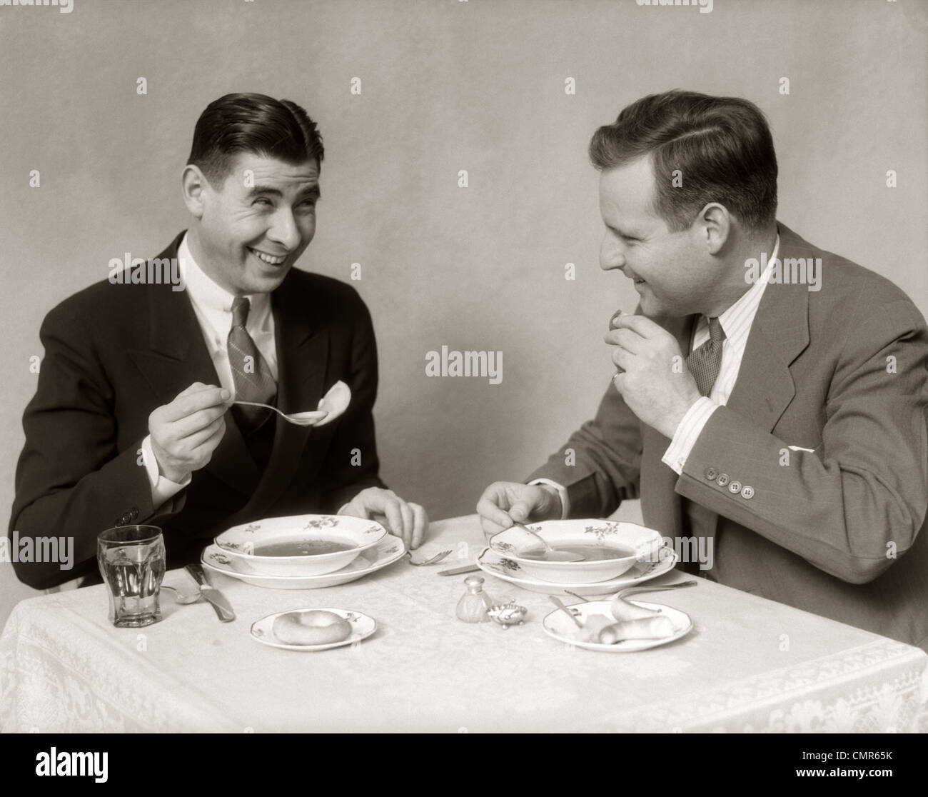 1930s TWO MEN DINING EATING SOUP SMILING Stock Photo