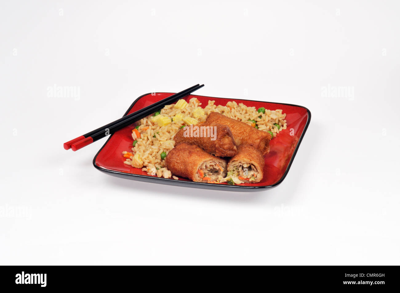 Shrimp fried rice and pork egg rolls meal on red plate with chopsticks Stock Photo